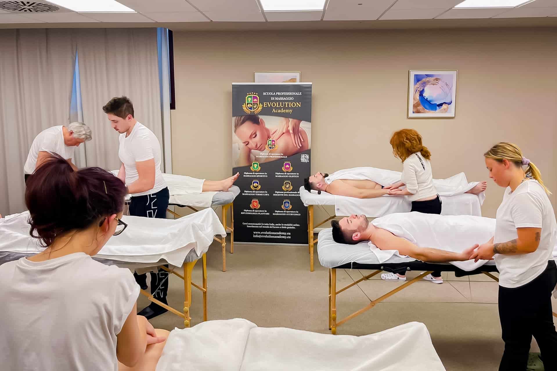Massaggiatori e studenti praticano tecniche di massaggio professionale in una sessione di formazione presso Evolution Academy.