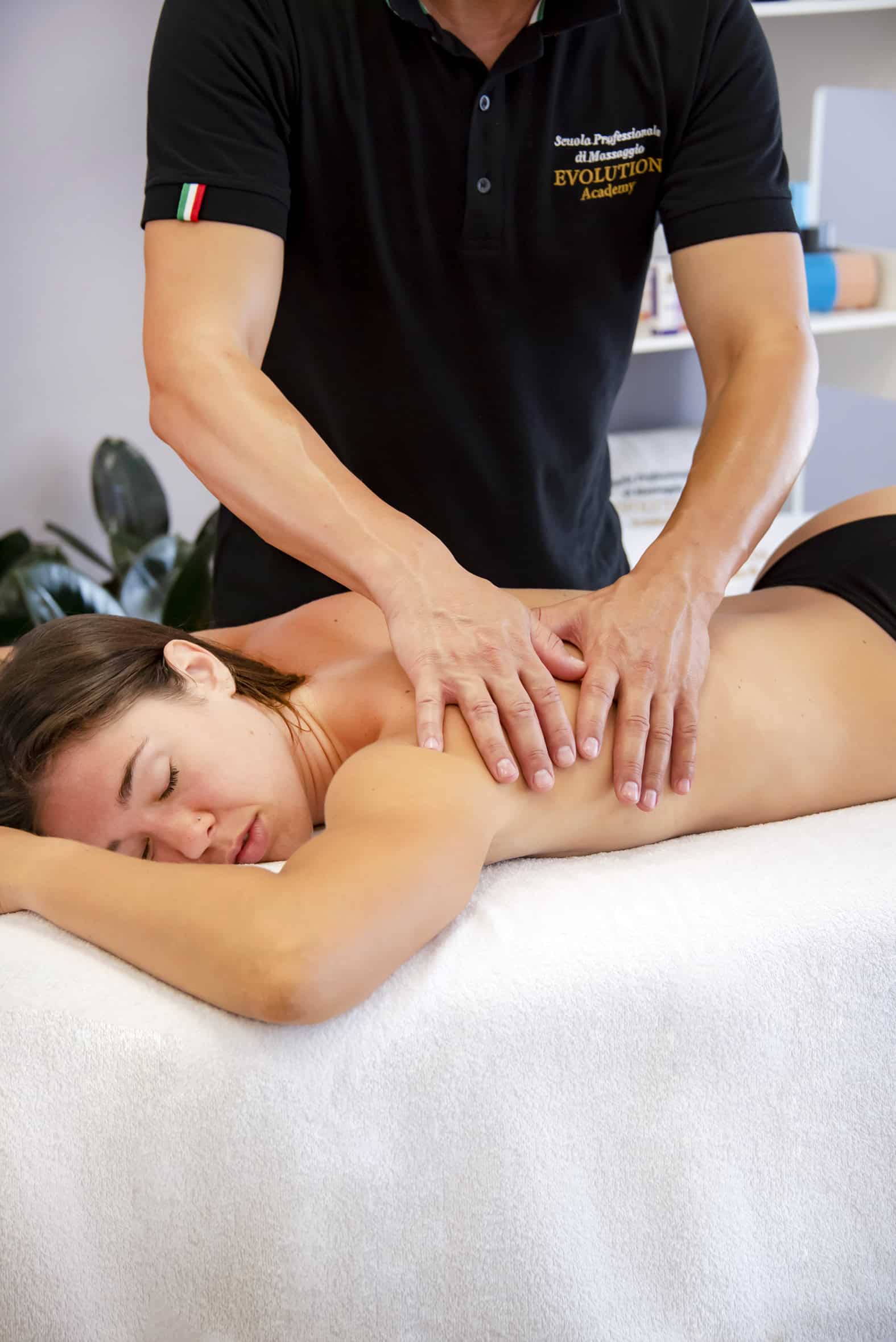 Massaggiatrice professionale dà massaggio rilassante a donna in terapia di benessere a scuola di massaggi Evolution Academy.