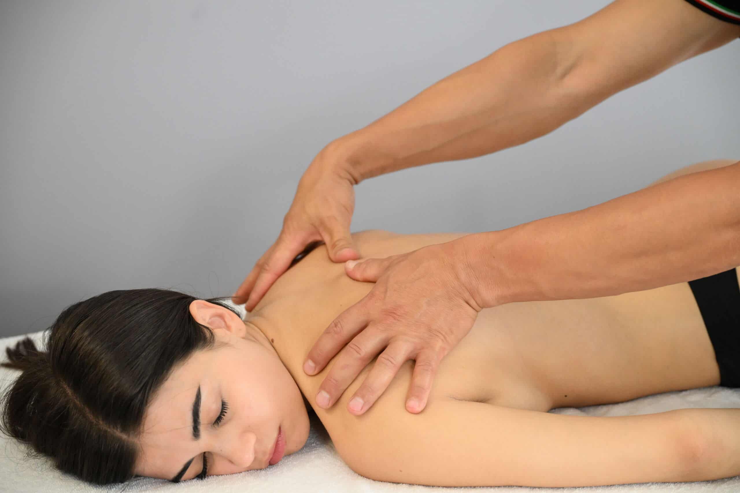 Massaggiatore che esegue massaggio terapeutico su una donna distesa su un lettino.