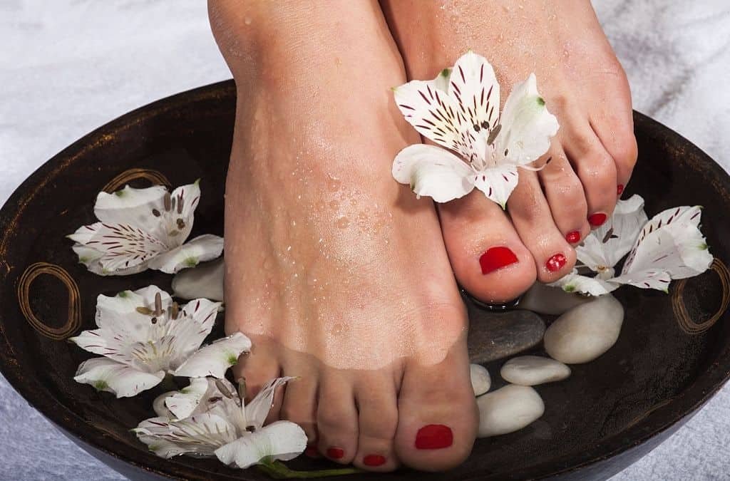 Pedicure con fiori e pietre, trattamenti di bellezza per piedi morbidi, relax e benessere.