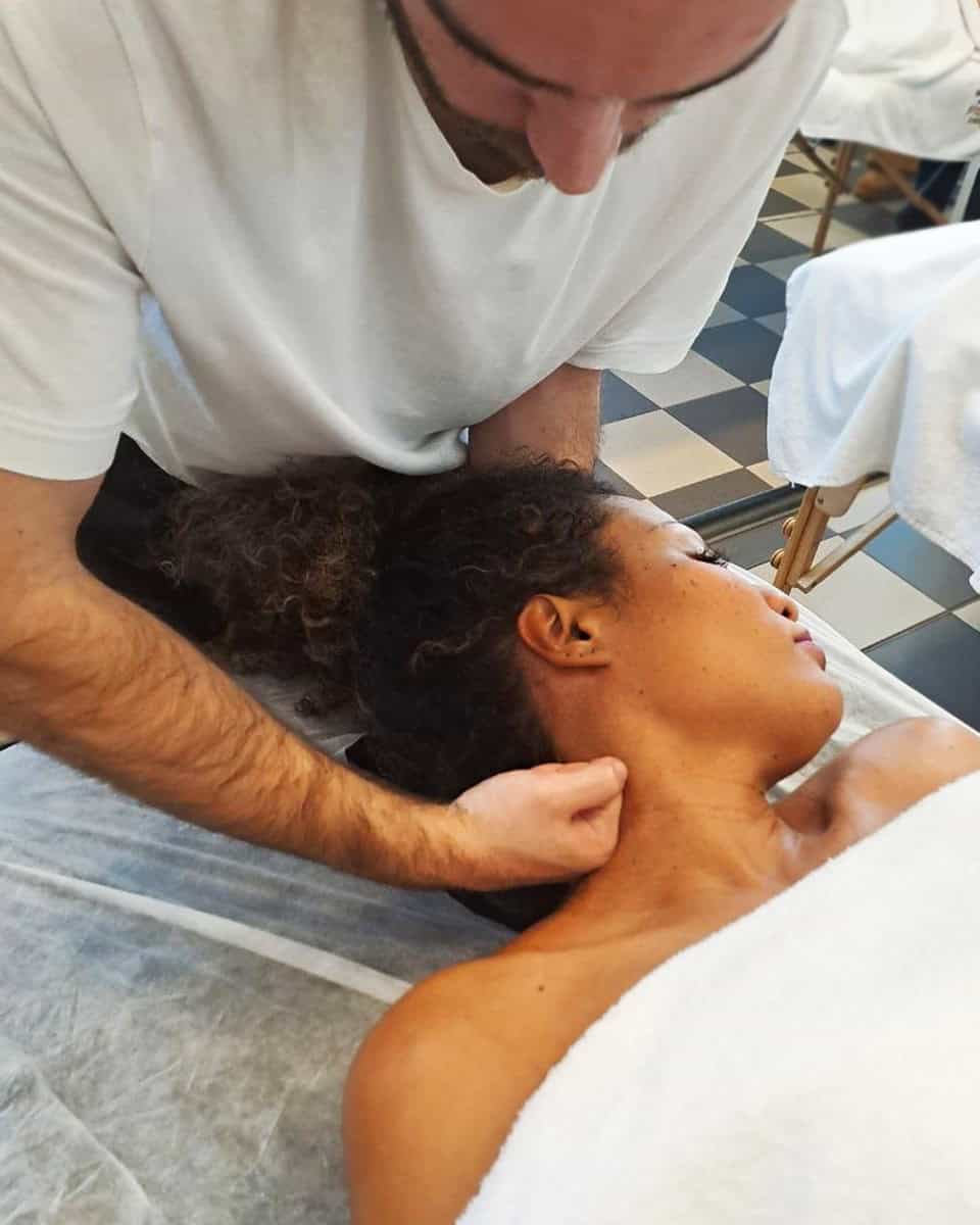 Massaggiatore che esegue terapia rilassante su donna sdraiata a letto.