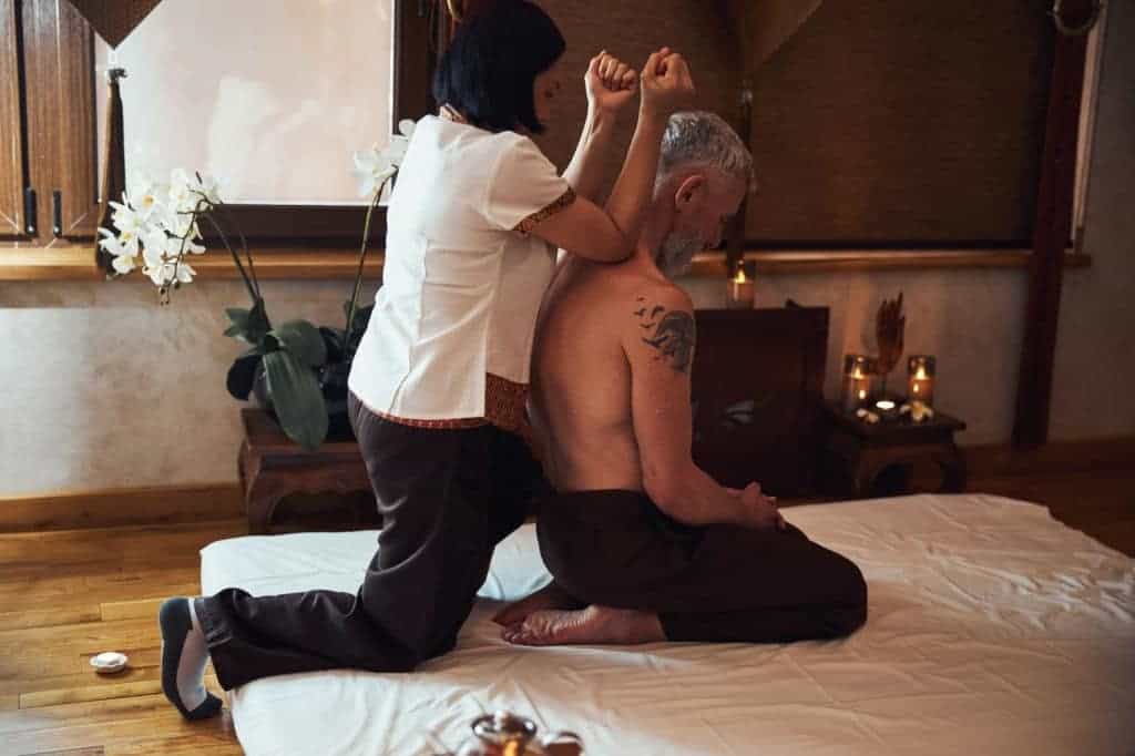 Massaggiatore e cliente durante sessione di terapia olistica, ambiente rilassante e accogliente.