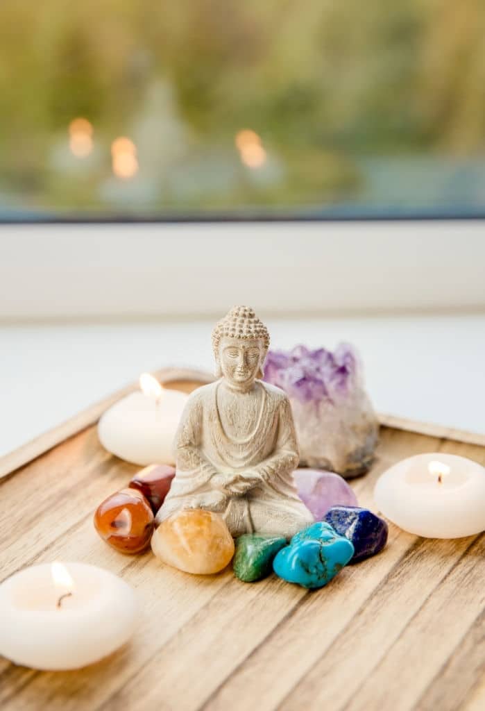Meditazione con statue di Buddha, candele e pietre curative per il benessere spirituale e relax.
