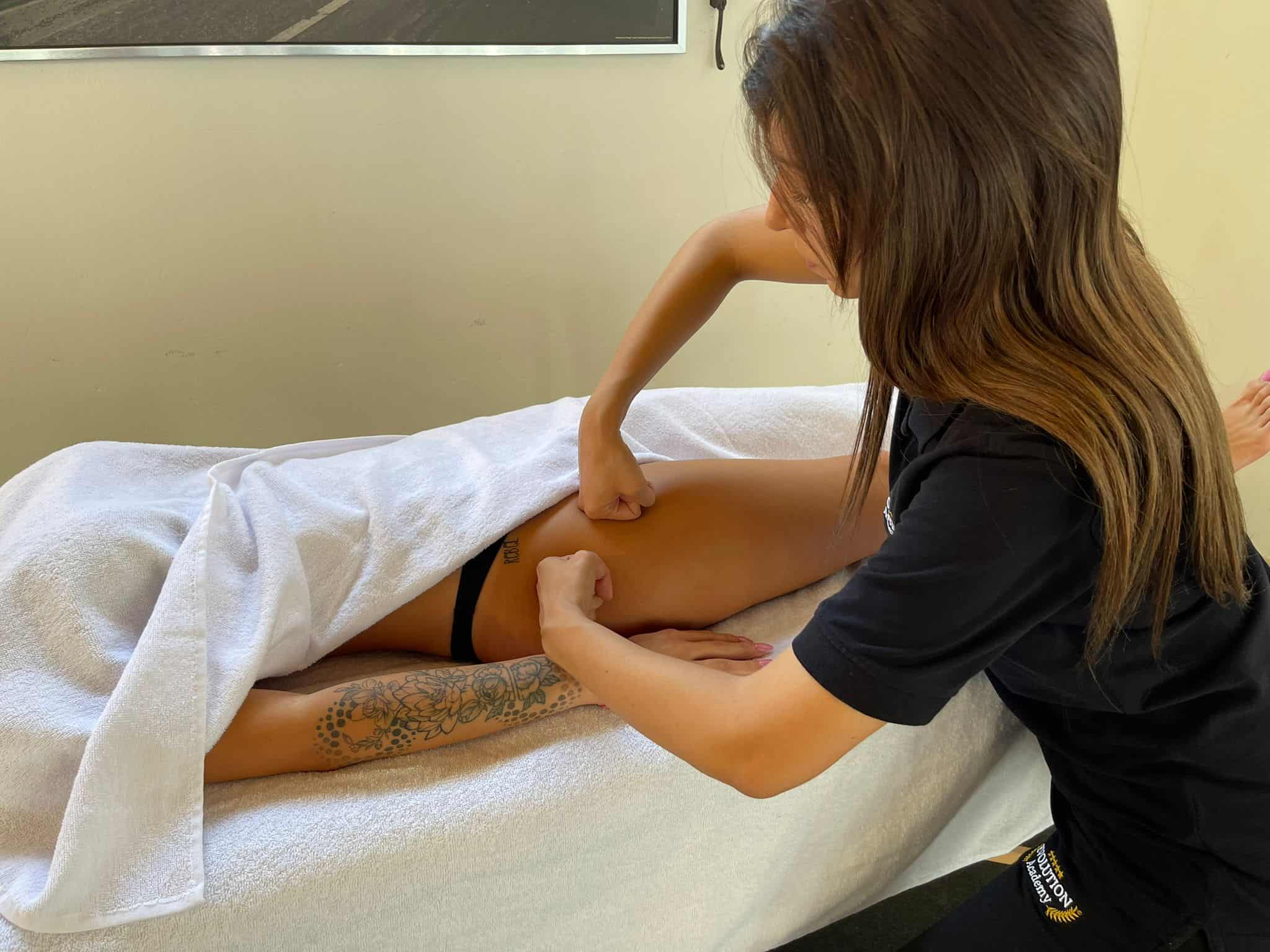 Massaggiatrice che dà un trattamento di massaggi terapeutici su una cliente distesa sul lettino.