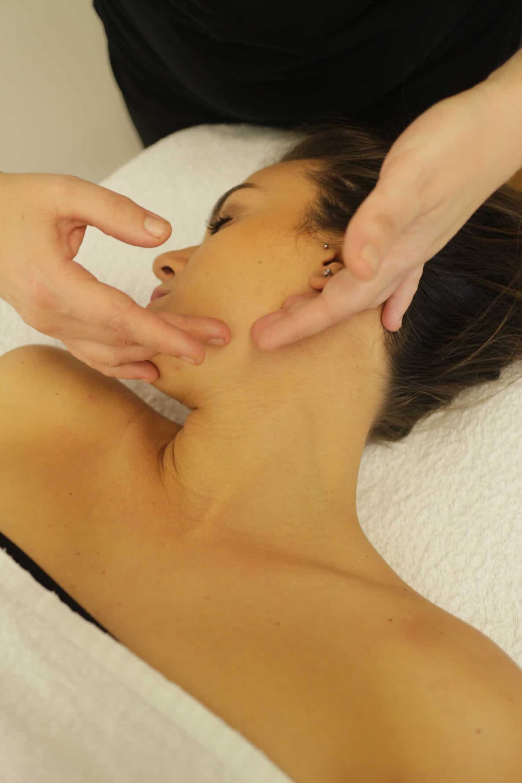 Massaggiatore che esegue un massaggio facciale su una donna distesa, promuovendo benessere e relax.