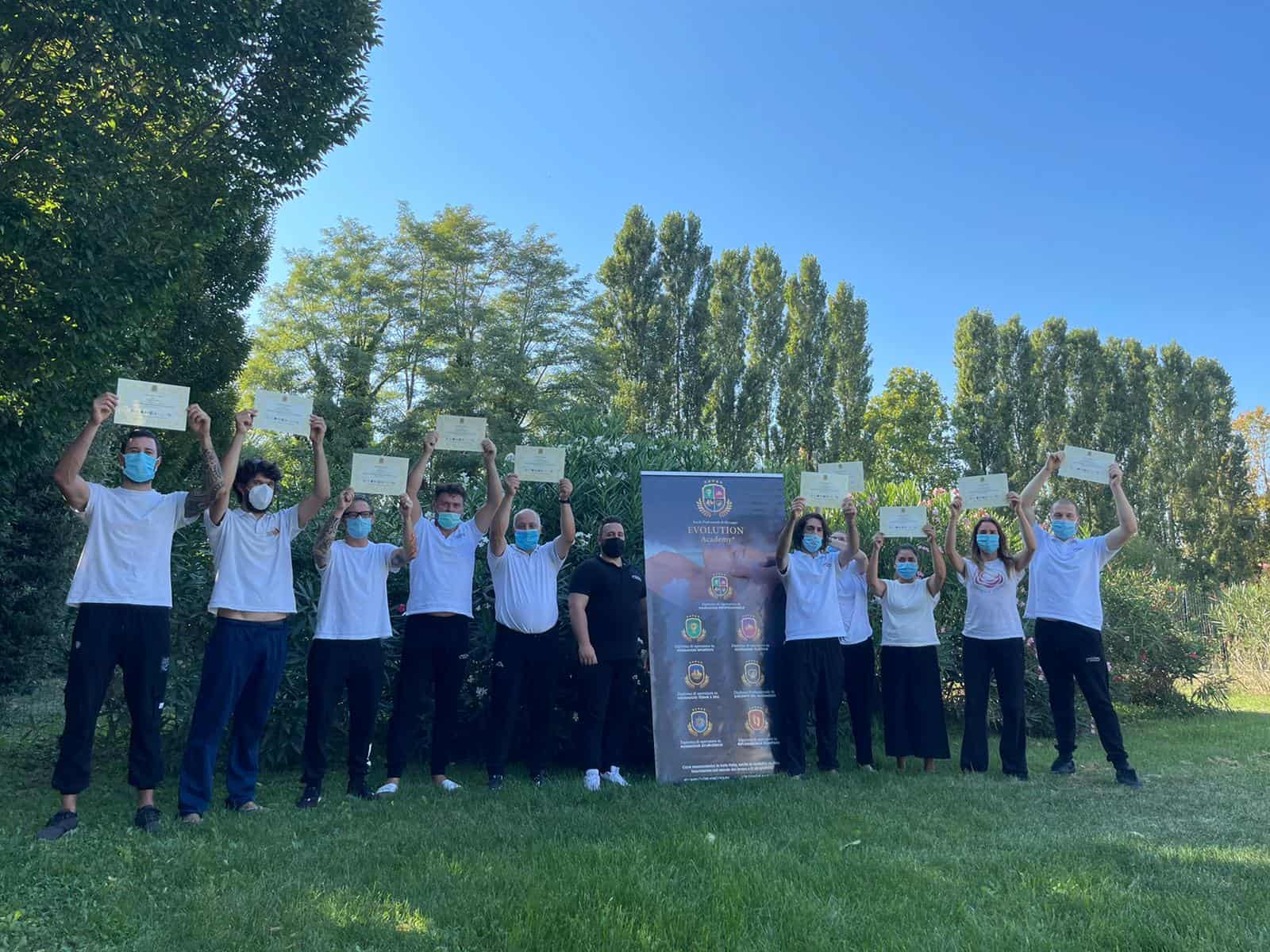 Certificazione di successo di studenti Evolution Academy® all'aperto, tutti con mascherina, che mostrano i diplomi recentemente conseguiti.