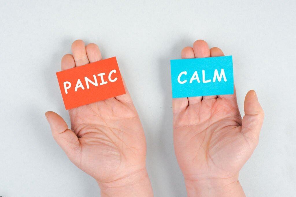 Ragazza che tiene schede con le parole "Panic" e "Calm" per la gestione dello stress e la crescita personale.