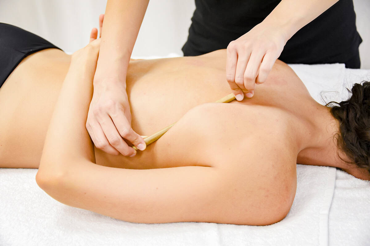 Massaggiatrice che esegue massaggio sportivo sulla schiena di una donna, trattamento benessere e relax.