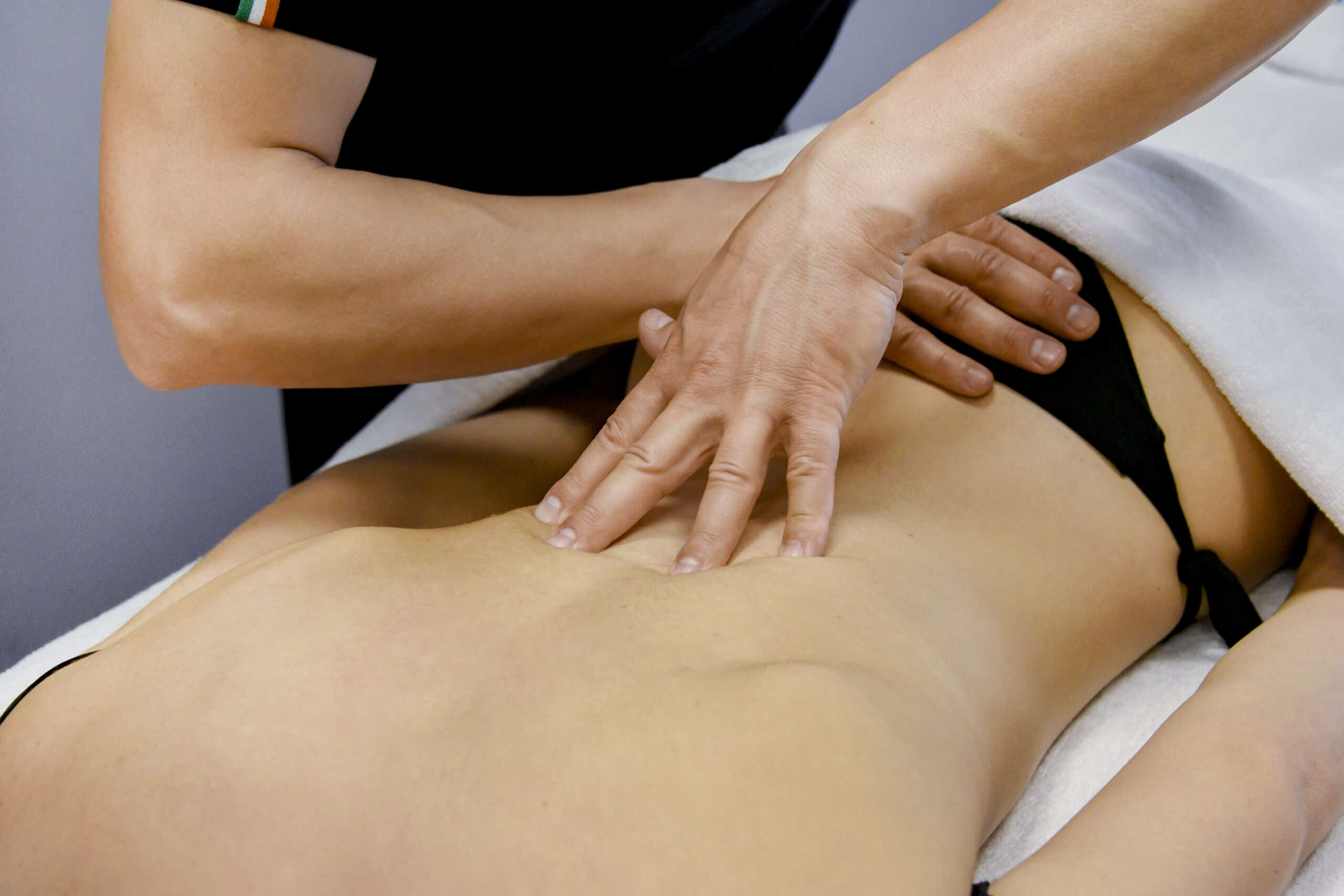 Massaggiatrice esegue massaggio rilassante su donna con bassa schiena in terapia wellness.