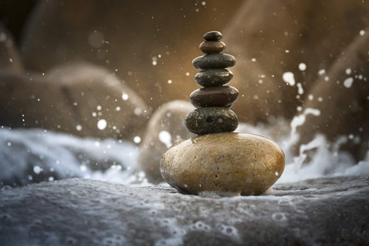 Equilibrio e meditazione con pietre su riva d'acqua.