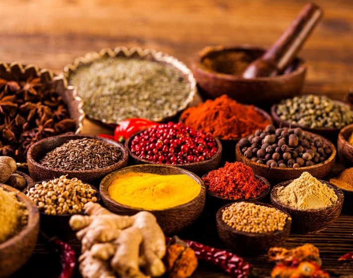 Misce di spezie e erbe aromatiche in ciotole di legno, perfette per la cucina salutare e naturale.